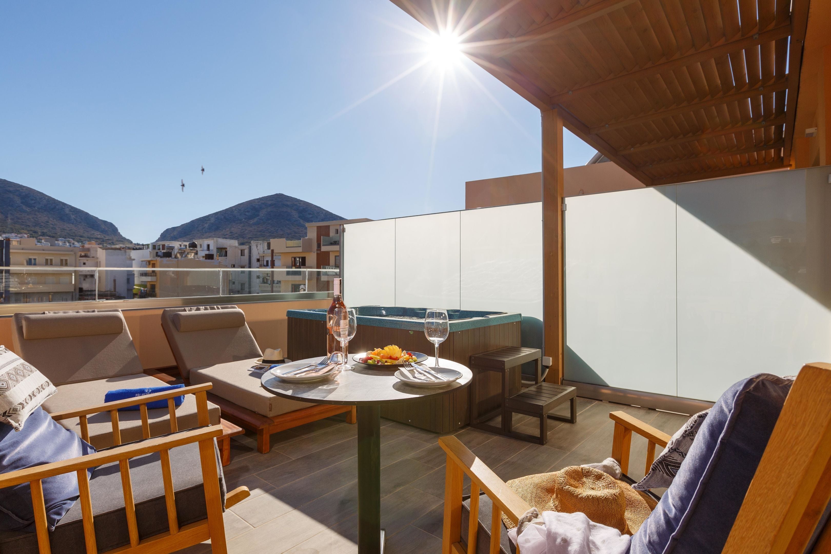 A rooftop terrace with a dining table, chairs, and a hot tub.