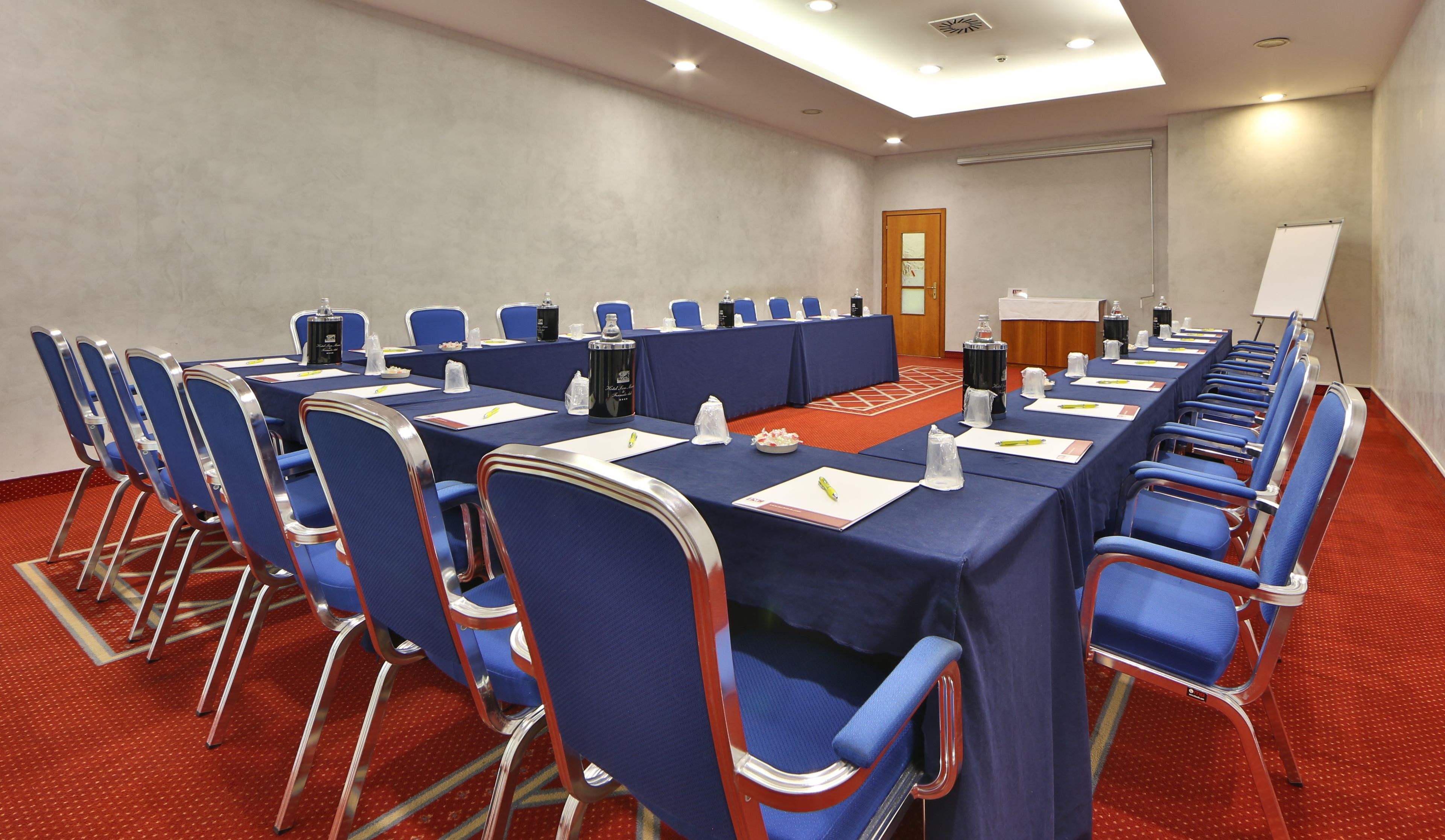 Ein Konferenzraum mit einem langen Tisch, blauen Stühlen und einer Wandtafel.