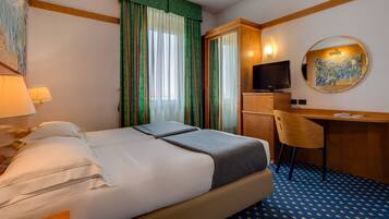 A hotel room with a bed, a desk, a chair, a television, and a mirror.