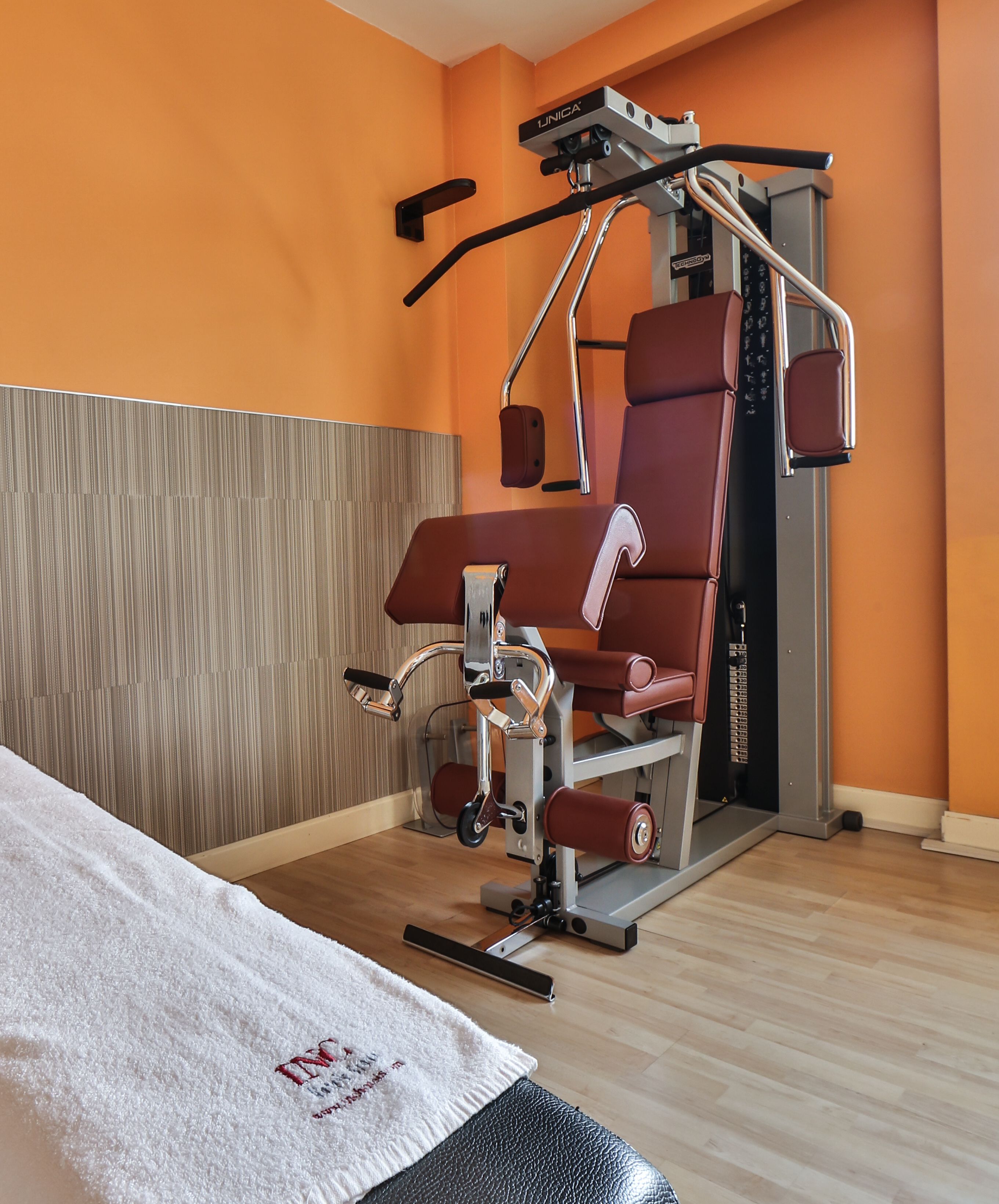 A modern gym with a pull-up bar, a weight bench, and a massage chair.