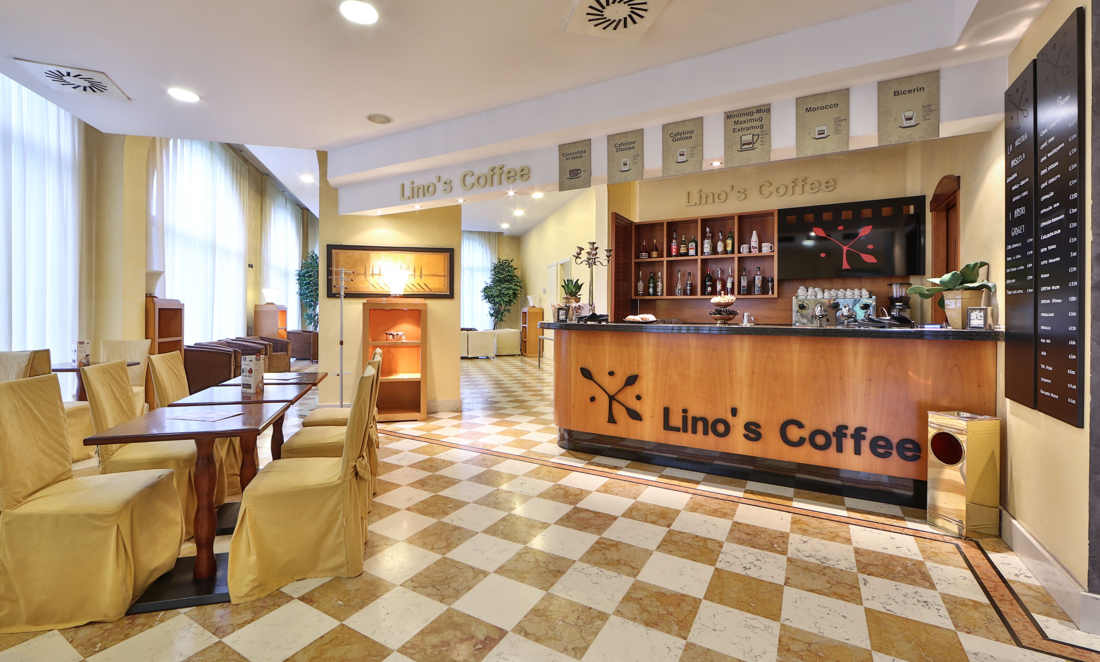 Ein Café-Interieur mit Schachbrettboden, Holztresen und Sitzbereich mit Stühlen und Tischen.