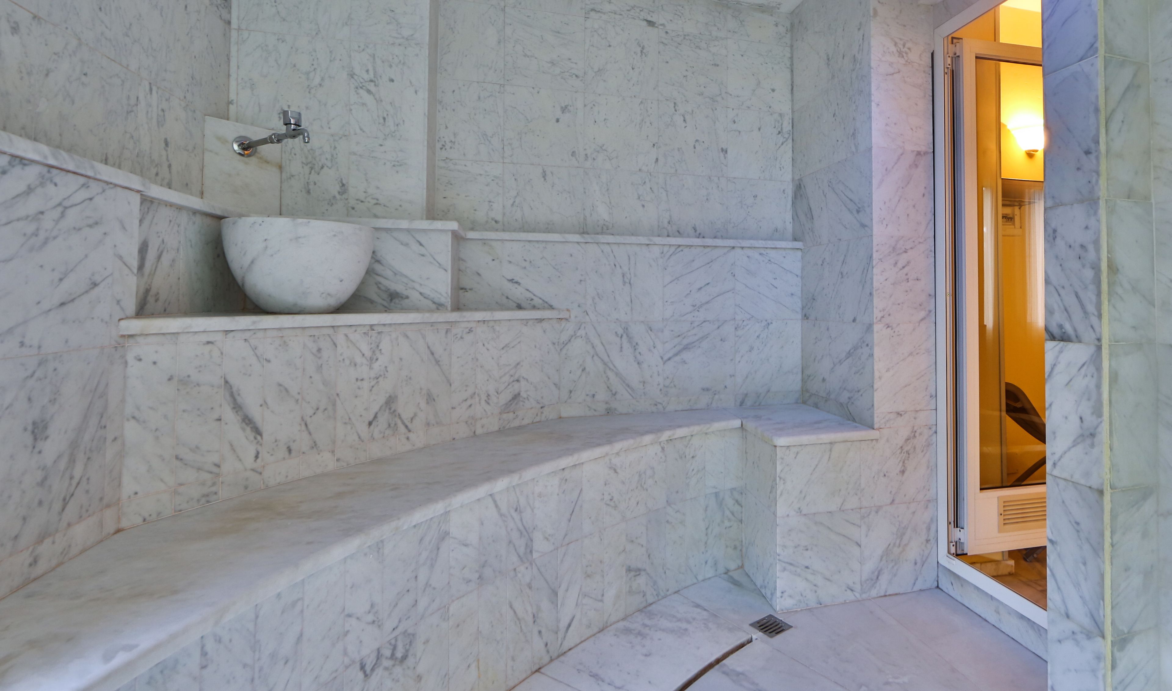 A marble bathroom with a built-in sink and steps leading to a shower area.