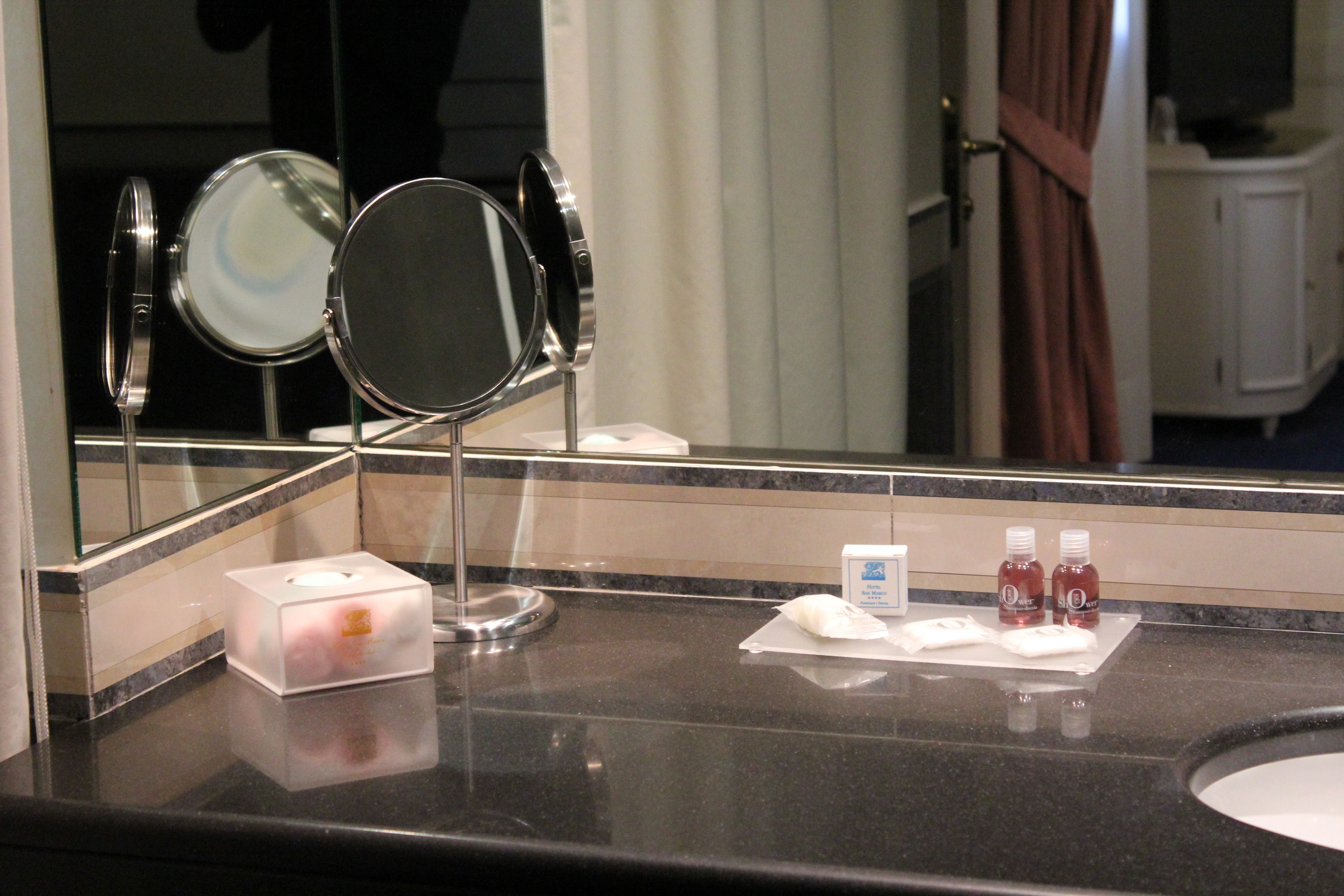 A hotel bathroom counter with a mirror, a tissue box, and two bottles of mouthwash.