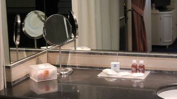 A hotel bathroom counter with a mirror, a tissue box, and two bottles of mouthwash.