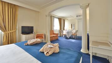 Una habitación de hotel con una cama grande, televisión, escritorio con silla y sofá.
