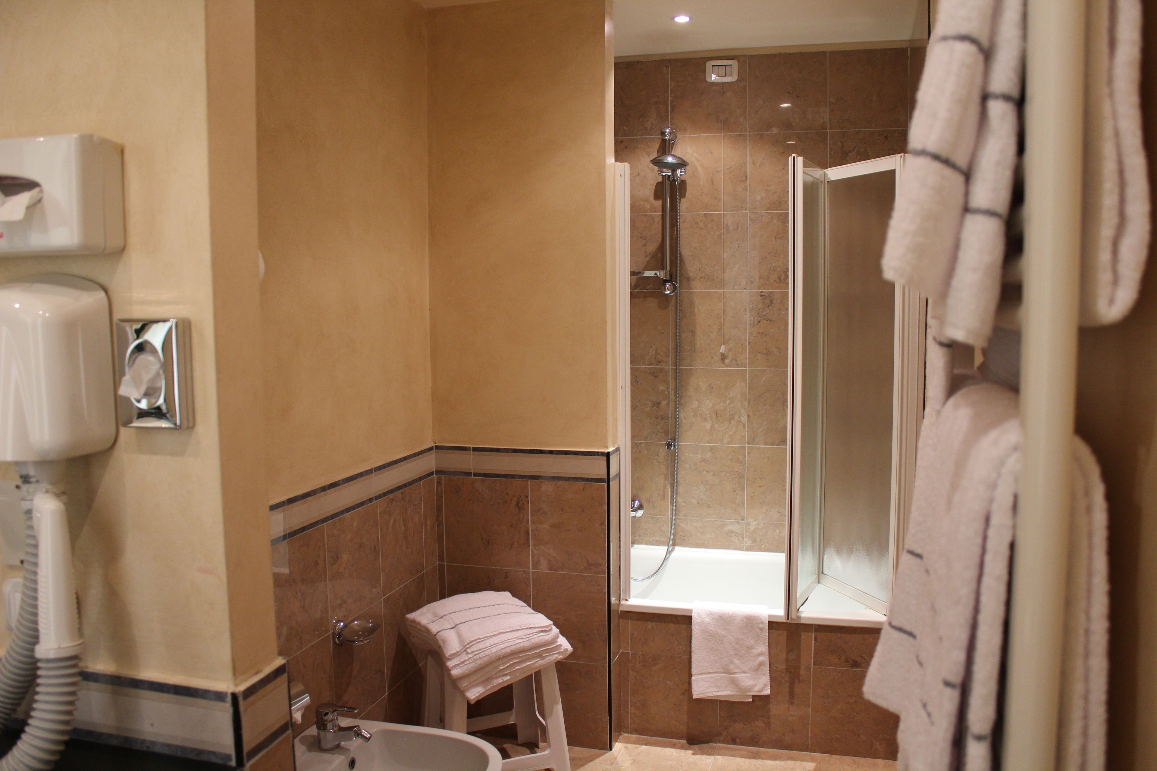 A bathroom with a shower, a sink, a towel rack, and a hairdryer.