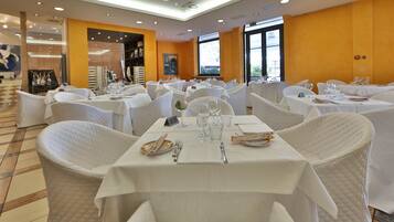 Un ristorante con tovaglie e sedie bianche, e un pavimento piastrellato.