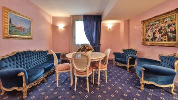 Een kamer met een ronde tafel, vier blauwe bekleden stoelen, een witte stoel en een blauw kamerbreed tapijt.