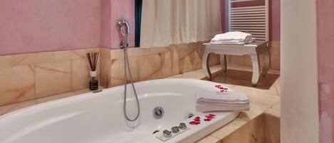 A bathroom with a large bathtub, a shower, and a vanity with a mirror.