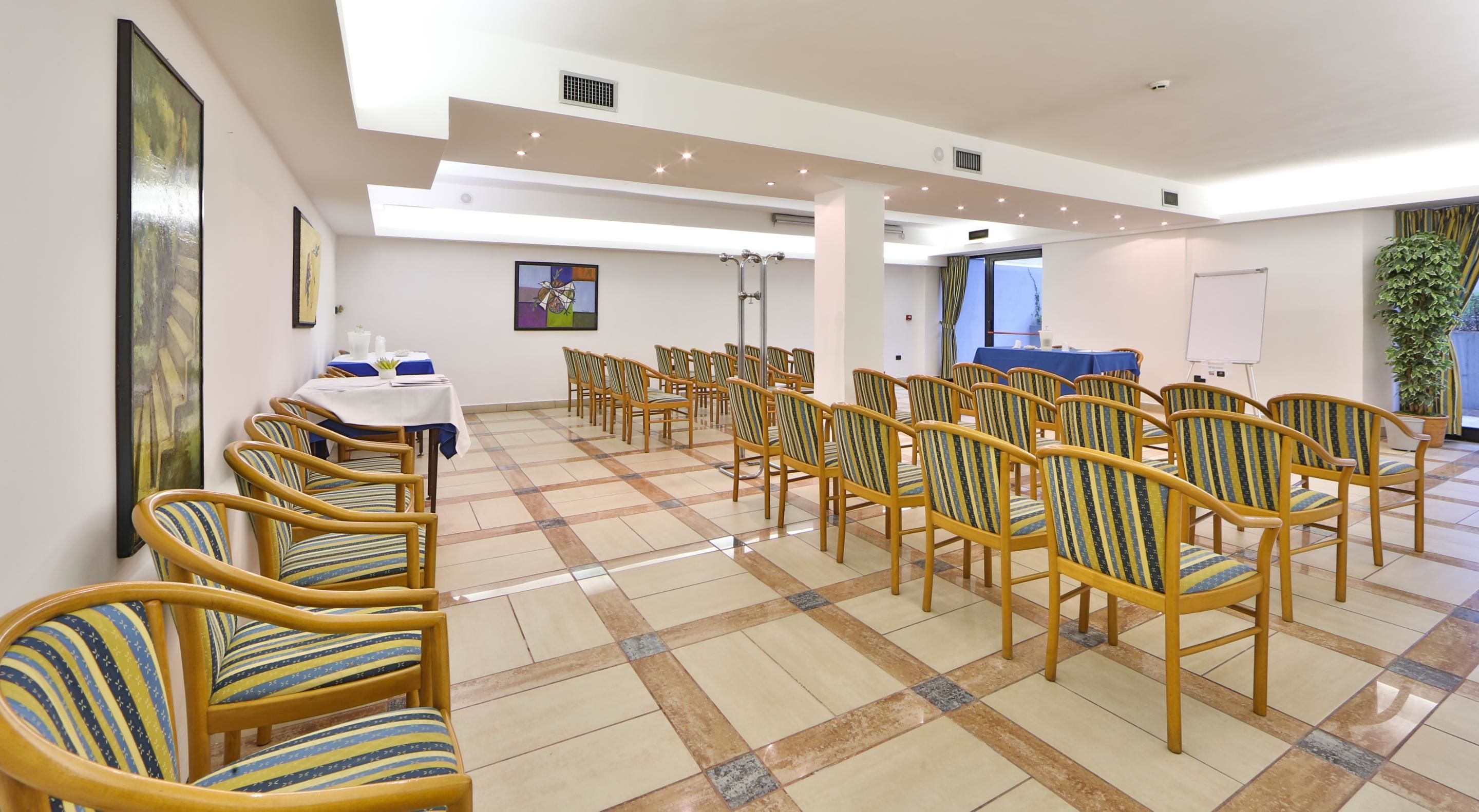 A conference room with rows of chairs, a whiteboard, and a table with a blue tablecloth.