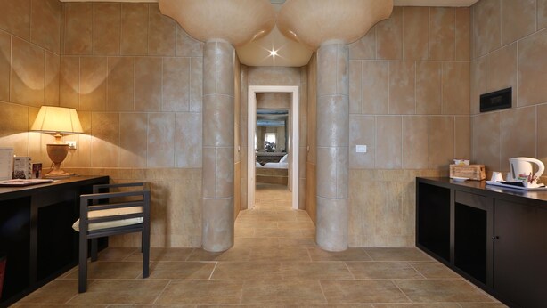 A hallway with a modern design, featuring two large columns, a desk with a lamp, and a chair. - Hotel San Marco & Formula Club (Noceto)