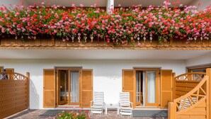 A hotel patio with stone flooring, wooden shutters, and a flower bed. - Landhotel Gabriele (Unterwoessen)