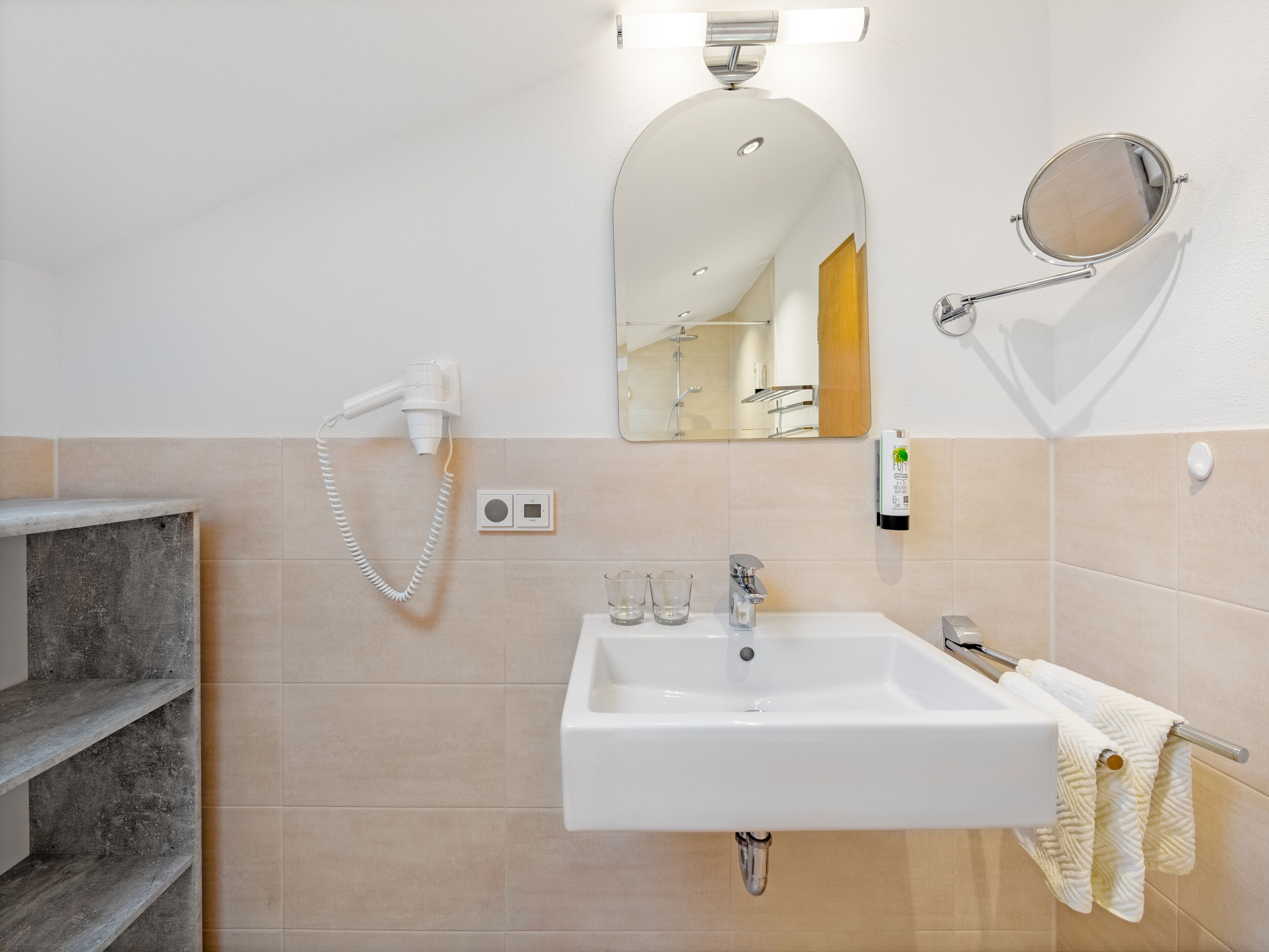 A bathroom with a white sink, a mirror, a hairdryer, and a towel rack.