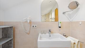 A bathroom with a white sink, a mirror, a hairdryer, and a towel rack.