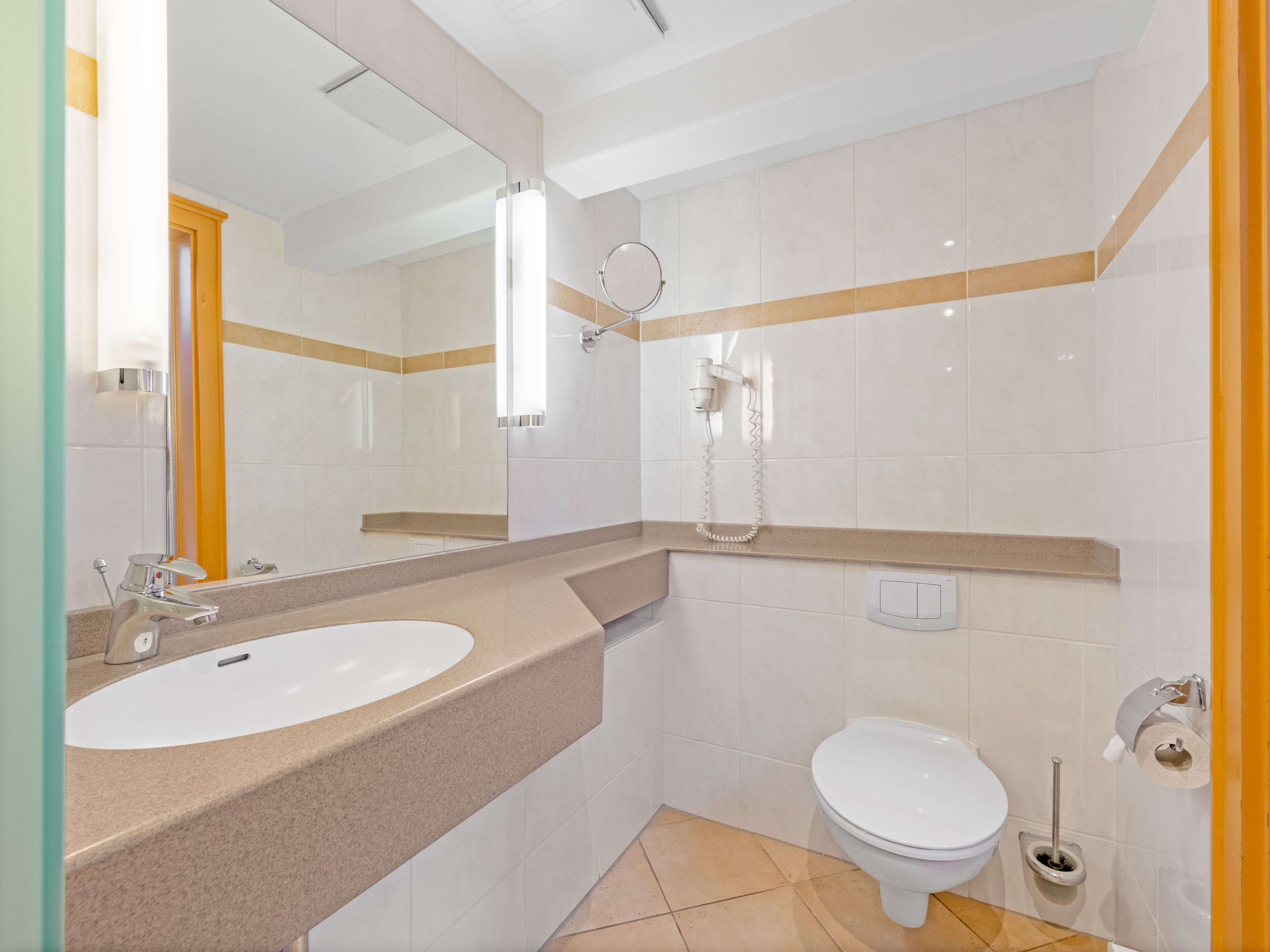 A bathroom with a sink, toilet, and a hairdryer mounted on the wall.