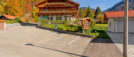 A hotel with a wooden facade, a parking lot, and a sign indicating it is a pension and restaurant.