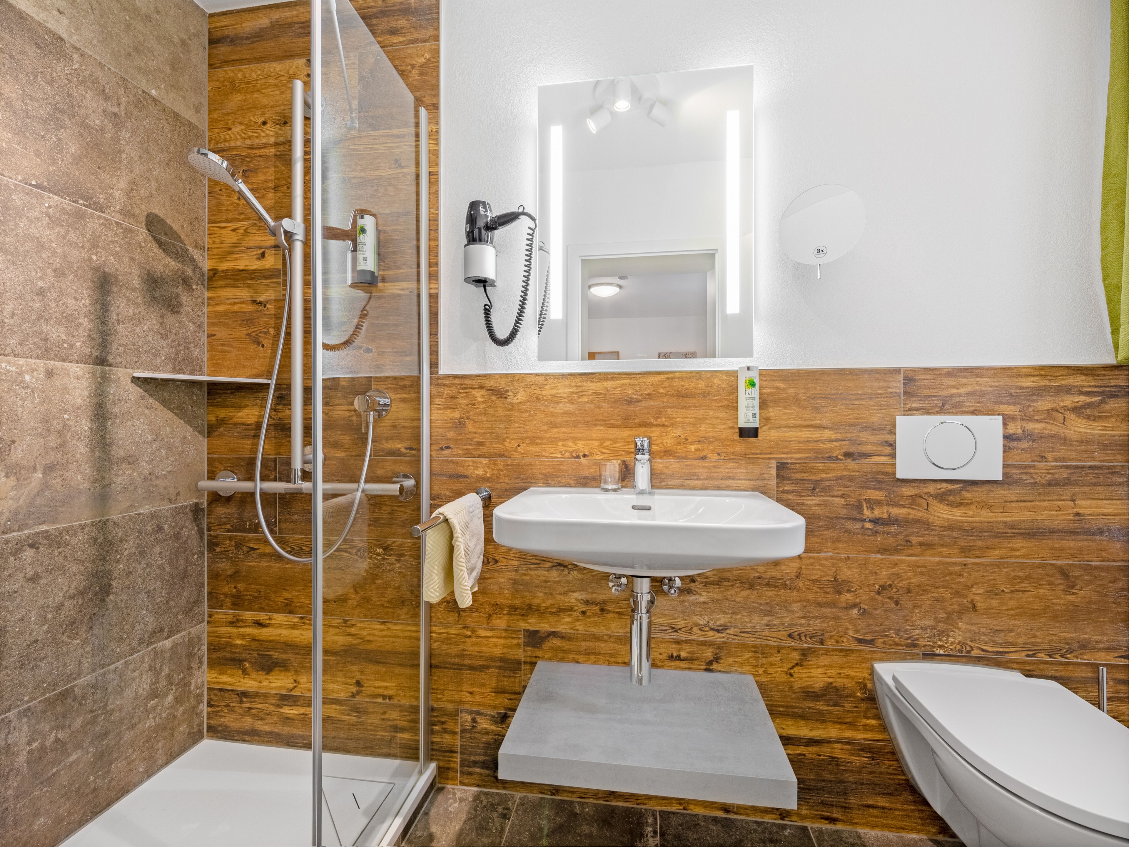 A modern bathroom with a glass shower enclosure, a white sink, and a toilet.