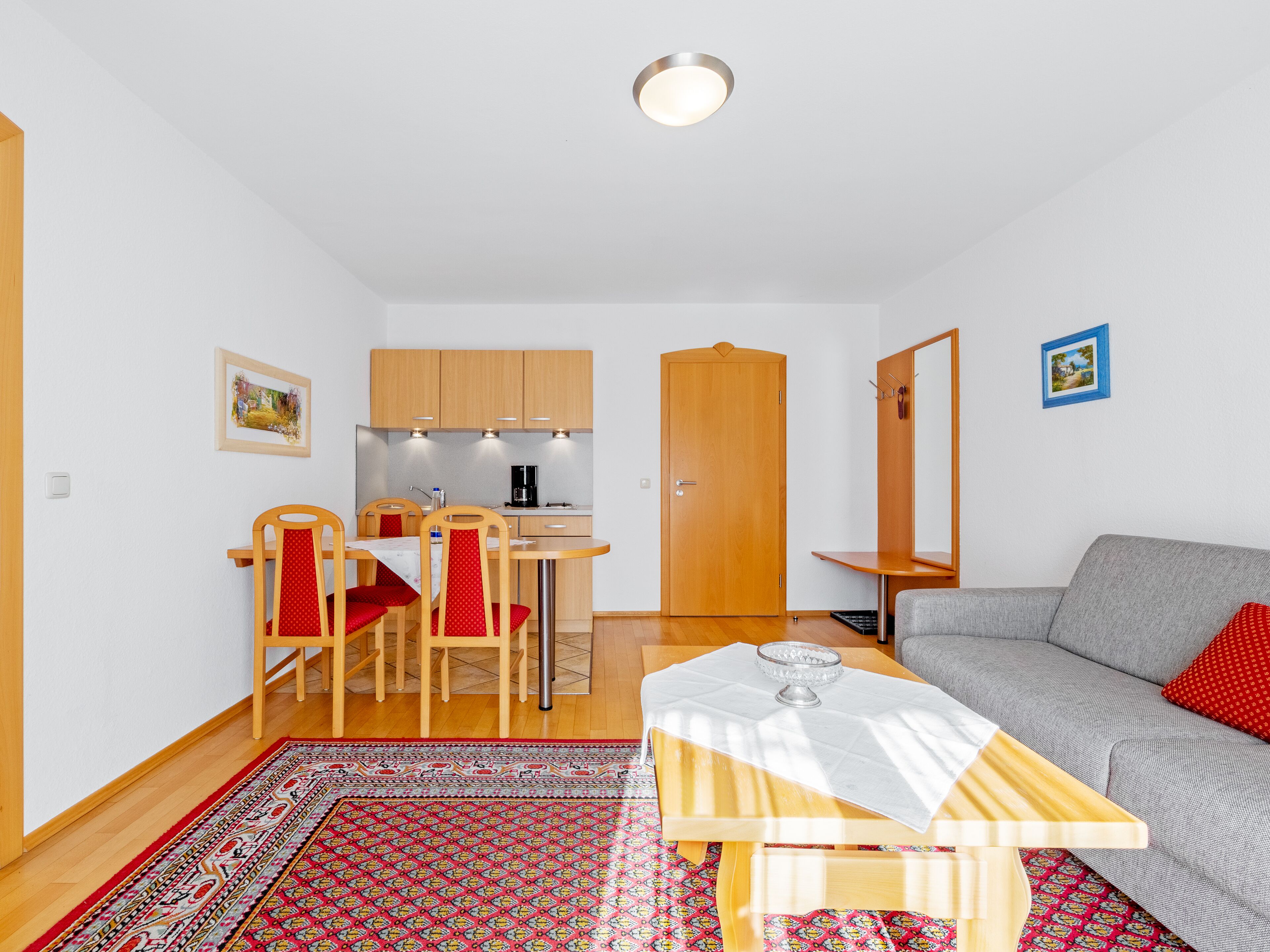 Un espacio habitable compacto con kitchenette, comedor y zona de estar.
