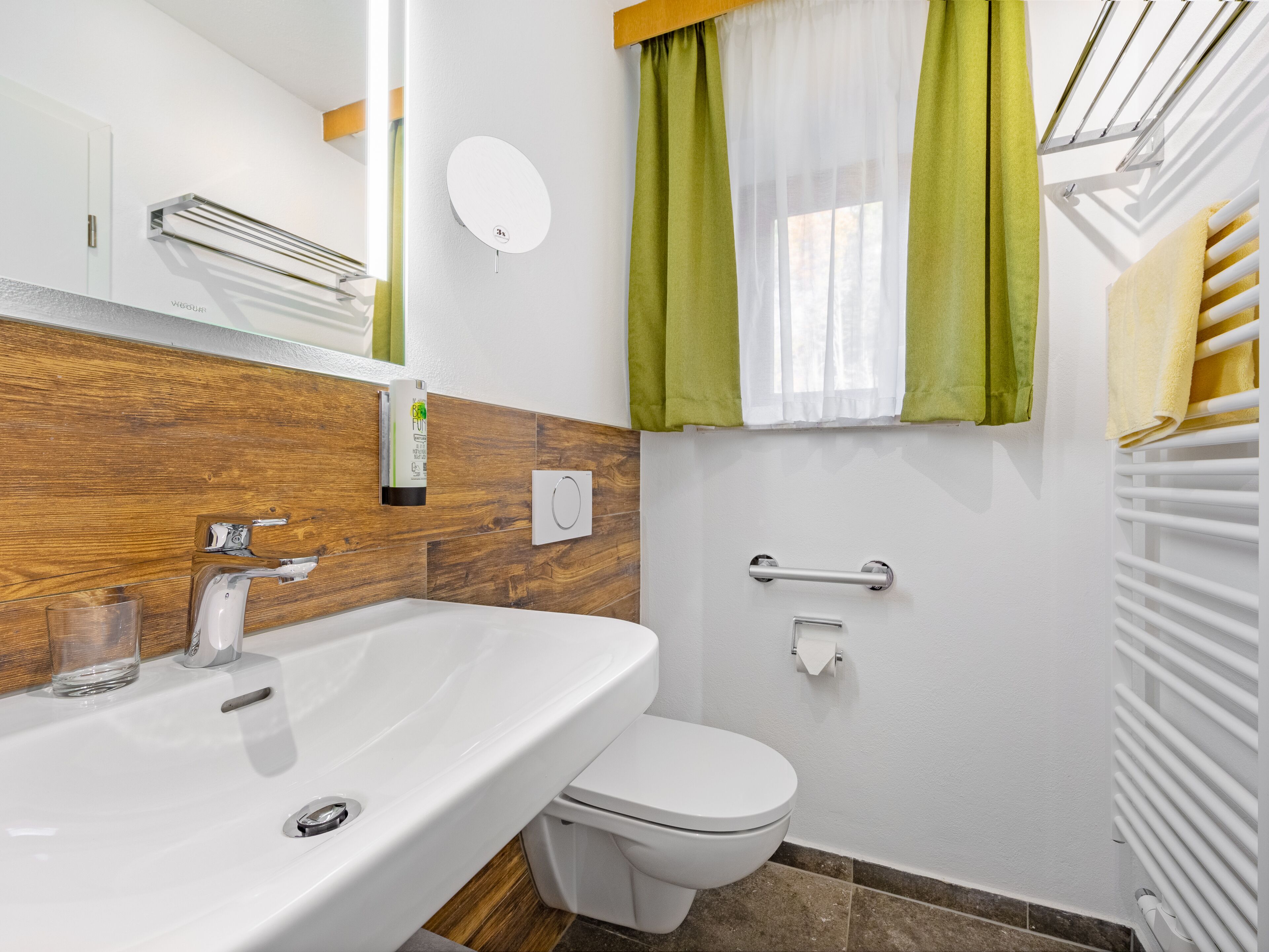 A modern bathroom with a white sink, toilet, and a mirror.