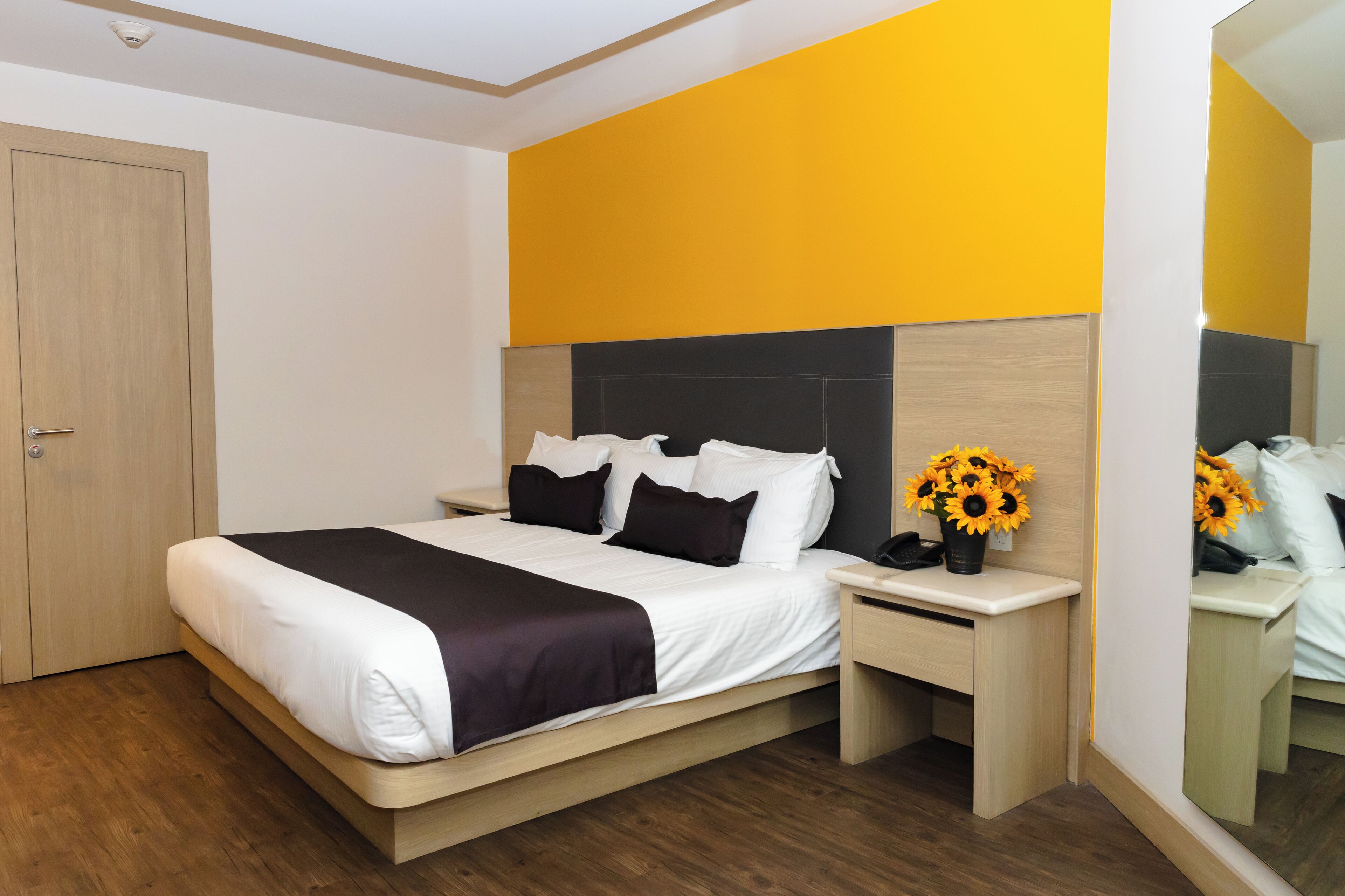 Habitació d'hotel moderna amb un llit gran, una taula de nit i un mirall.