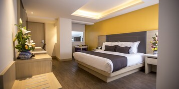 Een moderne hotelkamer met een groot bed, nachtkastjes, een bureau en een stoel.