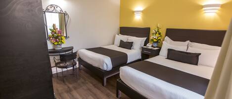 A hotel room with two beds, a desk, and a chair.