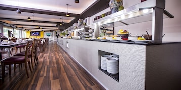 Een restaurant met een lange toonbank, houten vloeren en een aan de muur bevestigde televisie.