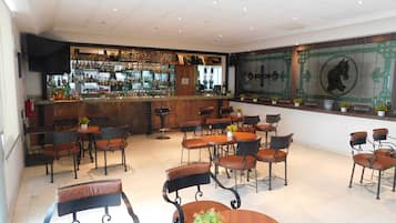 A bar area with multiple seating options, a bar counter, and a decorative wall with tiles and plants.