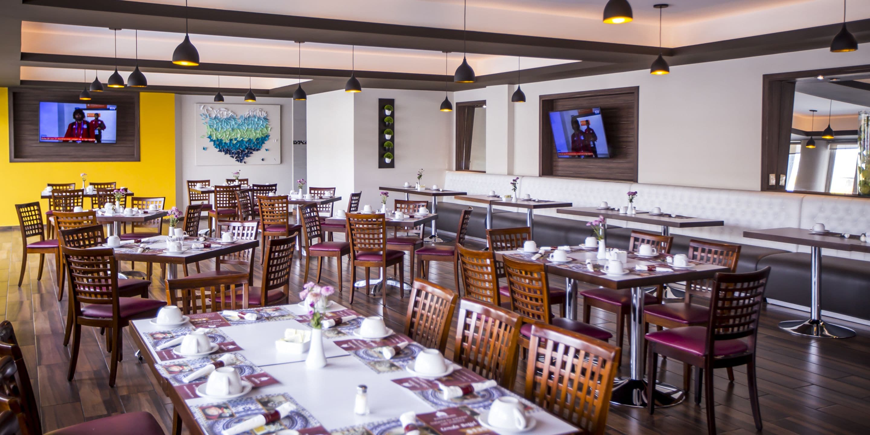 A restaurant with multiple dining tables and chairs, equipped with table settings and decorative items.