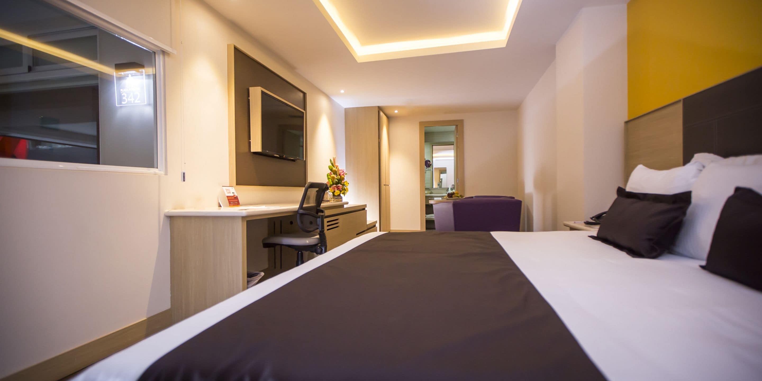 A modern hotel room with a large bed, a desk, and a television.