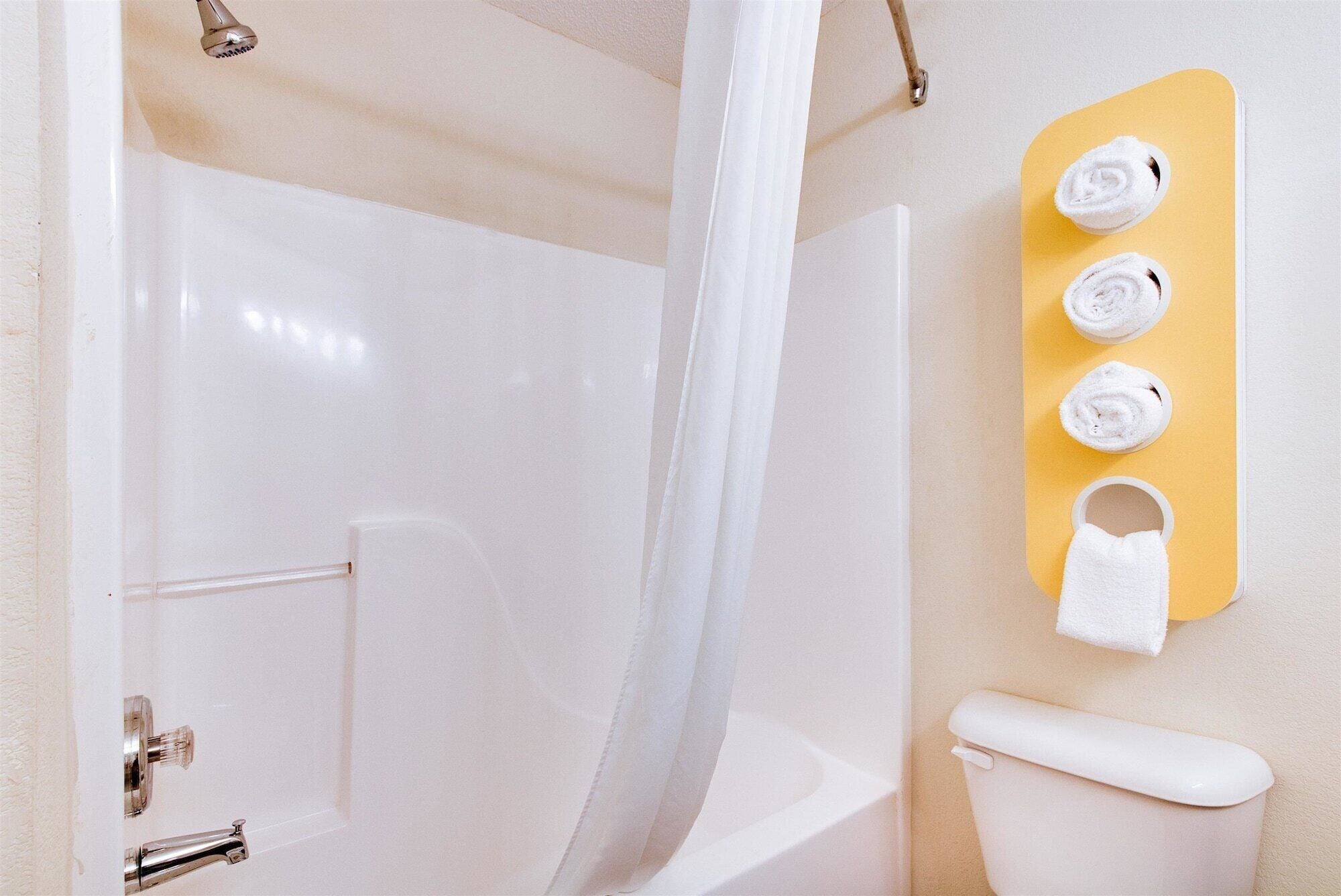 A bathroom with a bathtub, a toilet, and a towel rack with three towels.