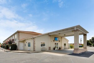 A motel with a covered parking area, a single-story building, and a sign indicating a 6-room motel.