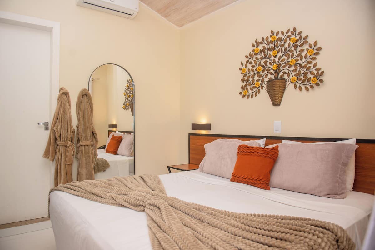 Una habitación de hotel con una cama grande, un espejo y un árbol decorativo en la pared.