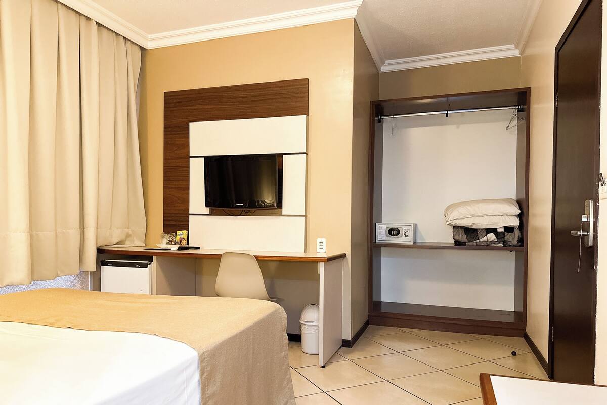 Une chambre d’hôtel équipée d’un lit, d’un bureau, d’une télévision, d’un four à micro-ondes et d’une douche.
