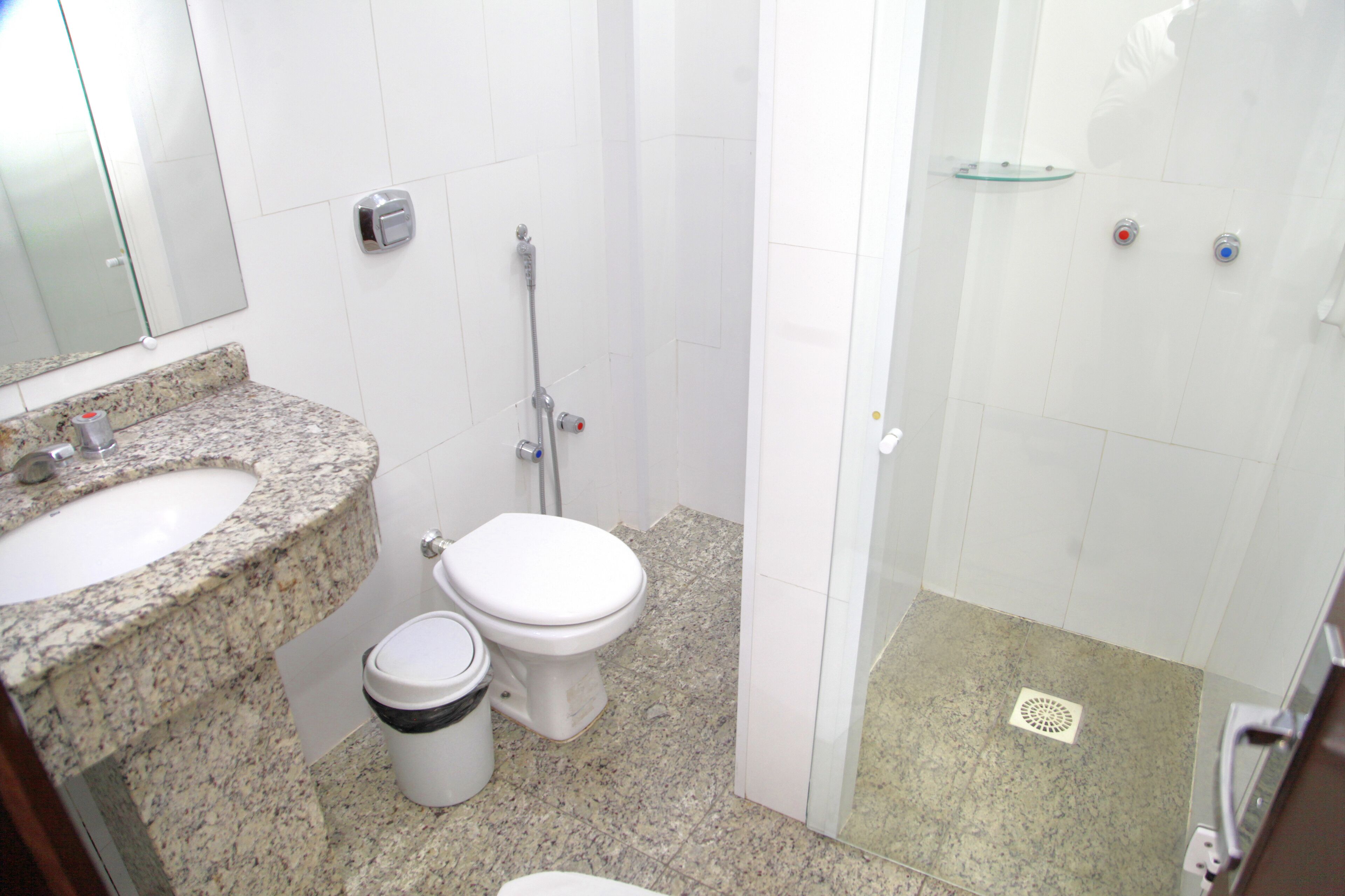 A bathroom with a granite countertop sink, a toilet, and a glass-enclosed shower area.