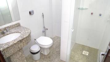 A bathroom with a granite countertop sink, a toilet, and a glass-enclosed shower area.
