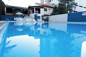 Una piscina al aire libre, sombrillas, sillones reclinables de piscina