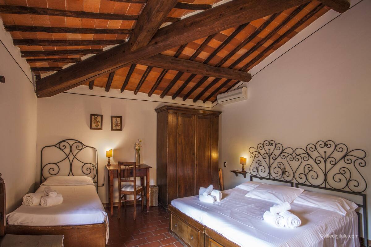Un dormitorio con dos camas, muebles de madera y techo rústico.