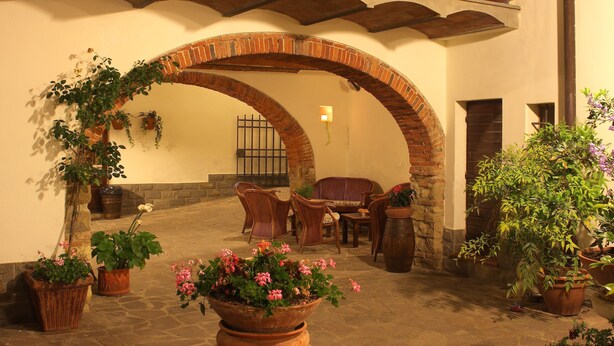 Un área de patio al aire libre con un arco de ladrillo, plantas en macetas y muebles de mimbre.