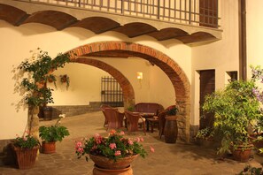 Un área de patio al aire libre con un arco de ladrillo, plantas en macetas y muebles de mimbre.