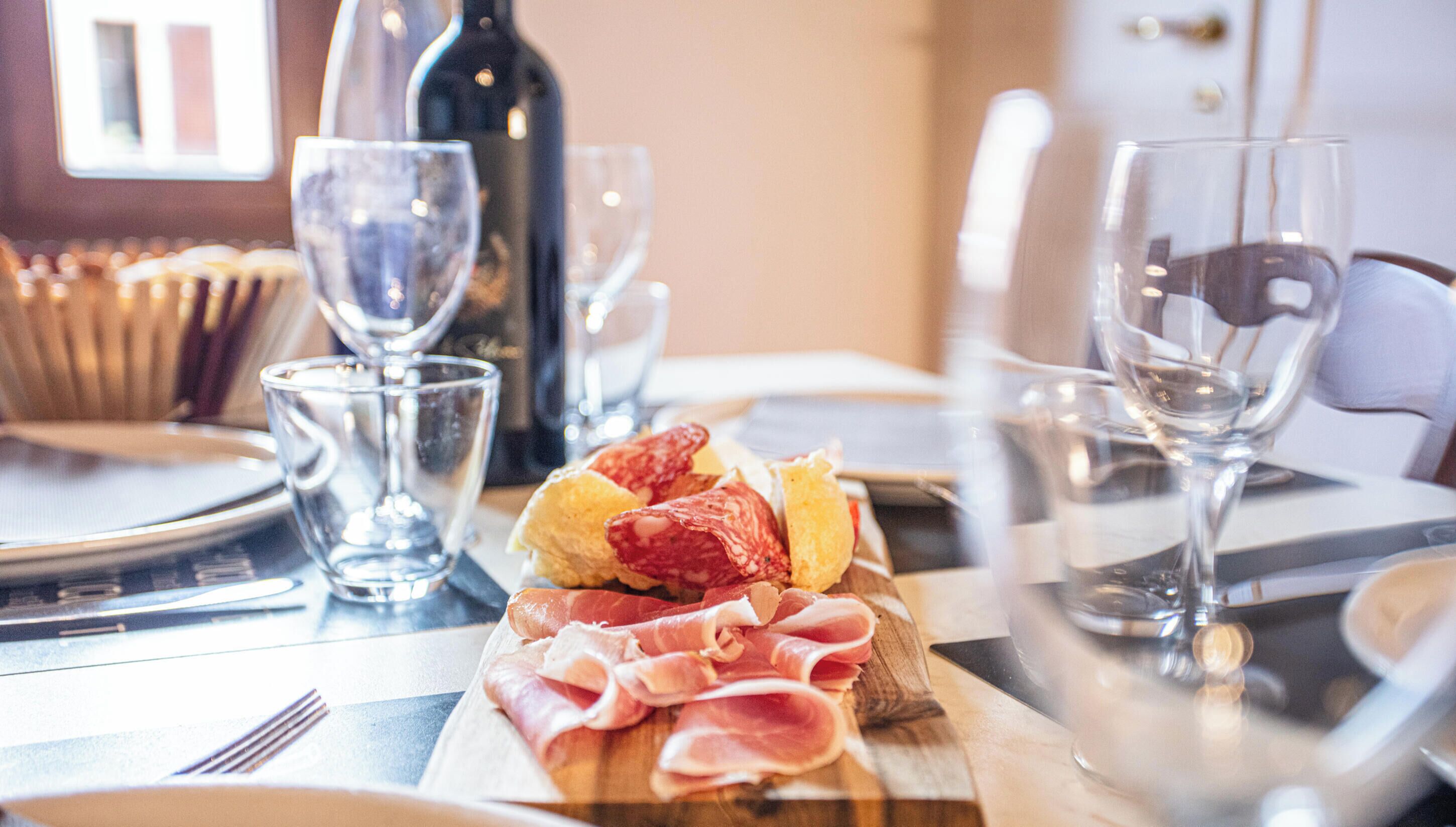 A dining table with a variety of food items, wine glasses, and a bottle of wine.