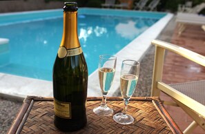 A bottle of champagne and two glasses on a woven table by a pool. - Hotel Tenuta Il Burchio (Figline e Incisa Valdarno)