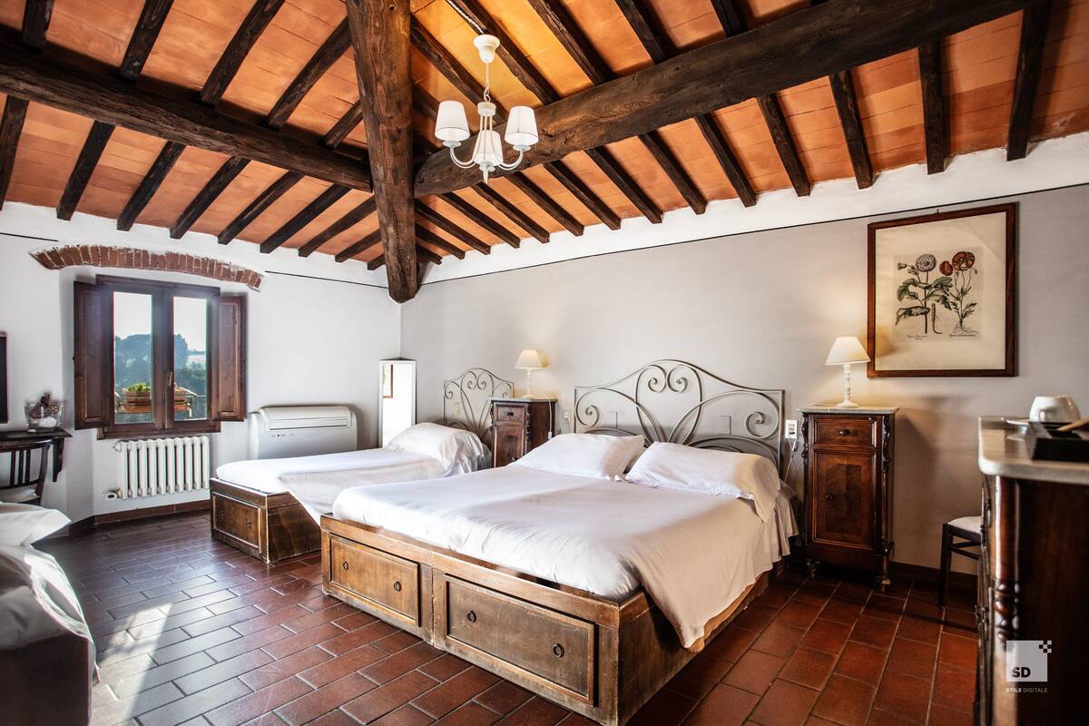 Un dormitorio con cama de madera, dos mesitas de noche, una ventana, un radiador y una araña.