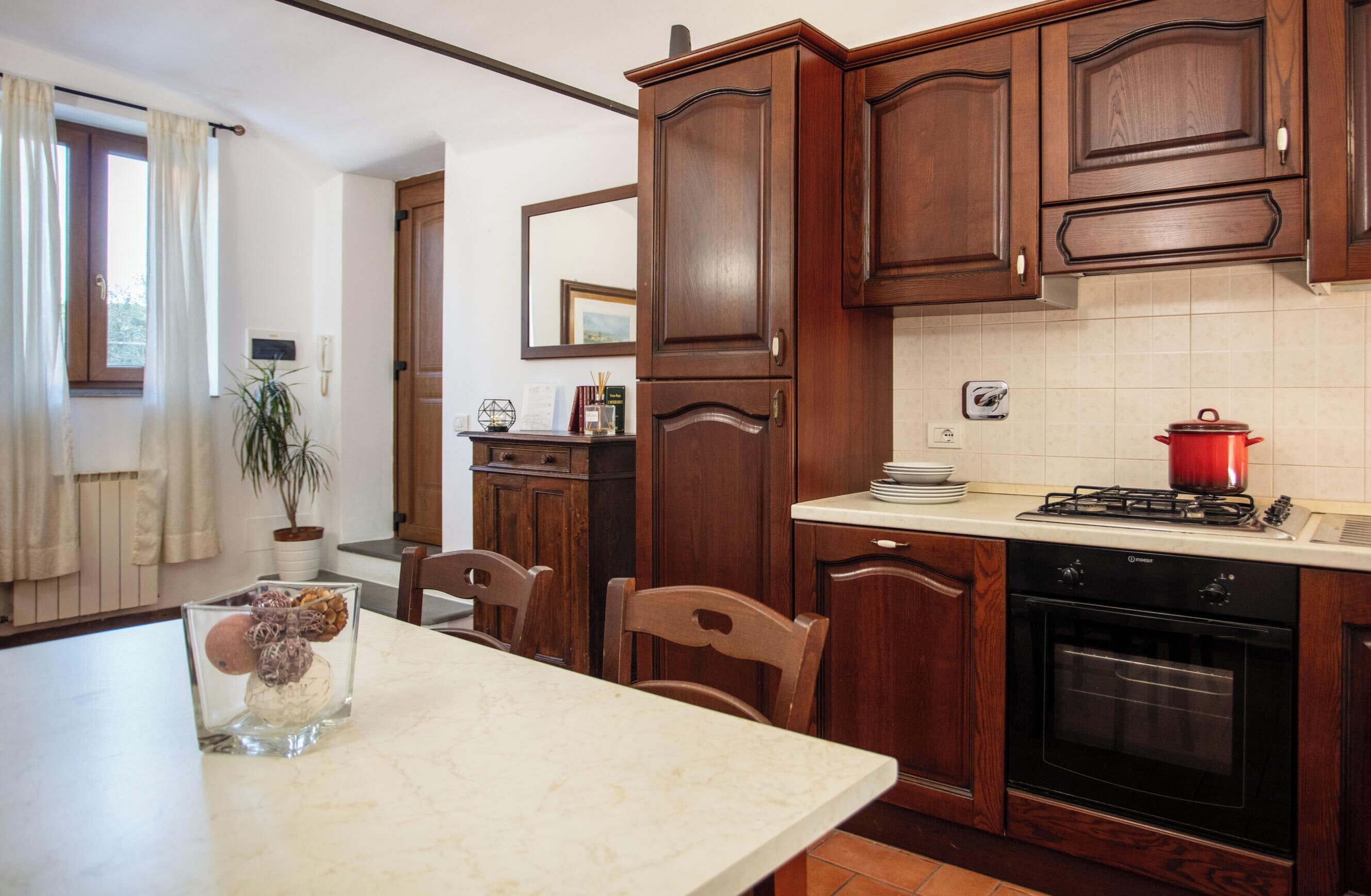 A kitchen with wooden cabinets, a stove, an oven, and a dining table with chairs.