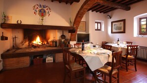 Un comedor con chimenea, vigas de madera y suelo de baldosas.