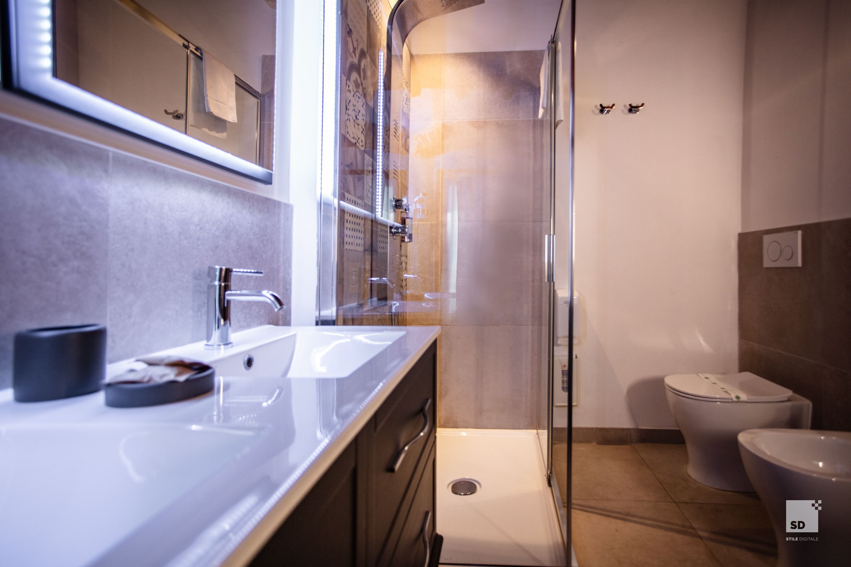 A modern bathroom with a glass shower enclosure, a white sink, and a toilet.