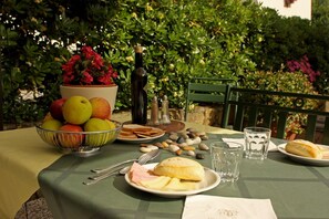 A table set outdoors with a variety of fruits, bread, and a bottle. - Hotel Tenuta Il Burchio (Figline e Incisa Valdarno)