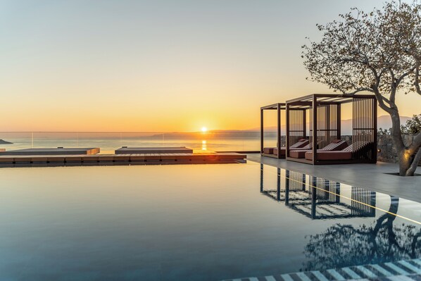 Una piscina al aire libre, sombrillas, sillones reclinables de piscina