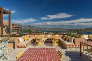 Un patio al aire libre con asientos y una mesa, con vistas a un paisaje pintoresco.