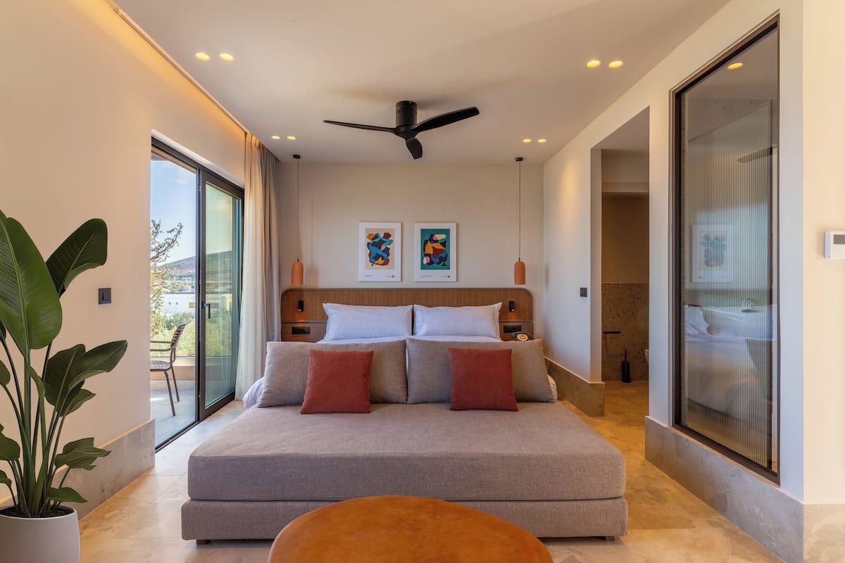 A modern bedroom with a large bed, a ceiling fan, and artwork on the wall.